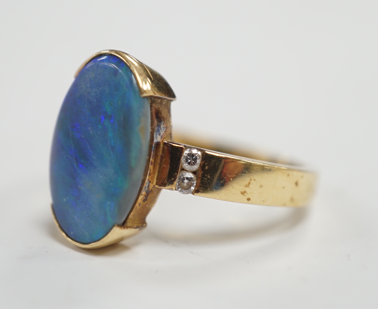 A yellow metal and black opal oval dress ring, with diamond chip shoulders, size P, gross weight 5.7 grams.